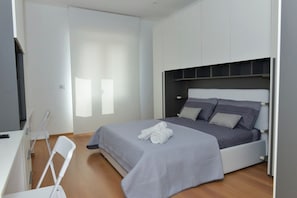 Un dormitorio moderno con una cama, un escritorio y una silla.