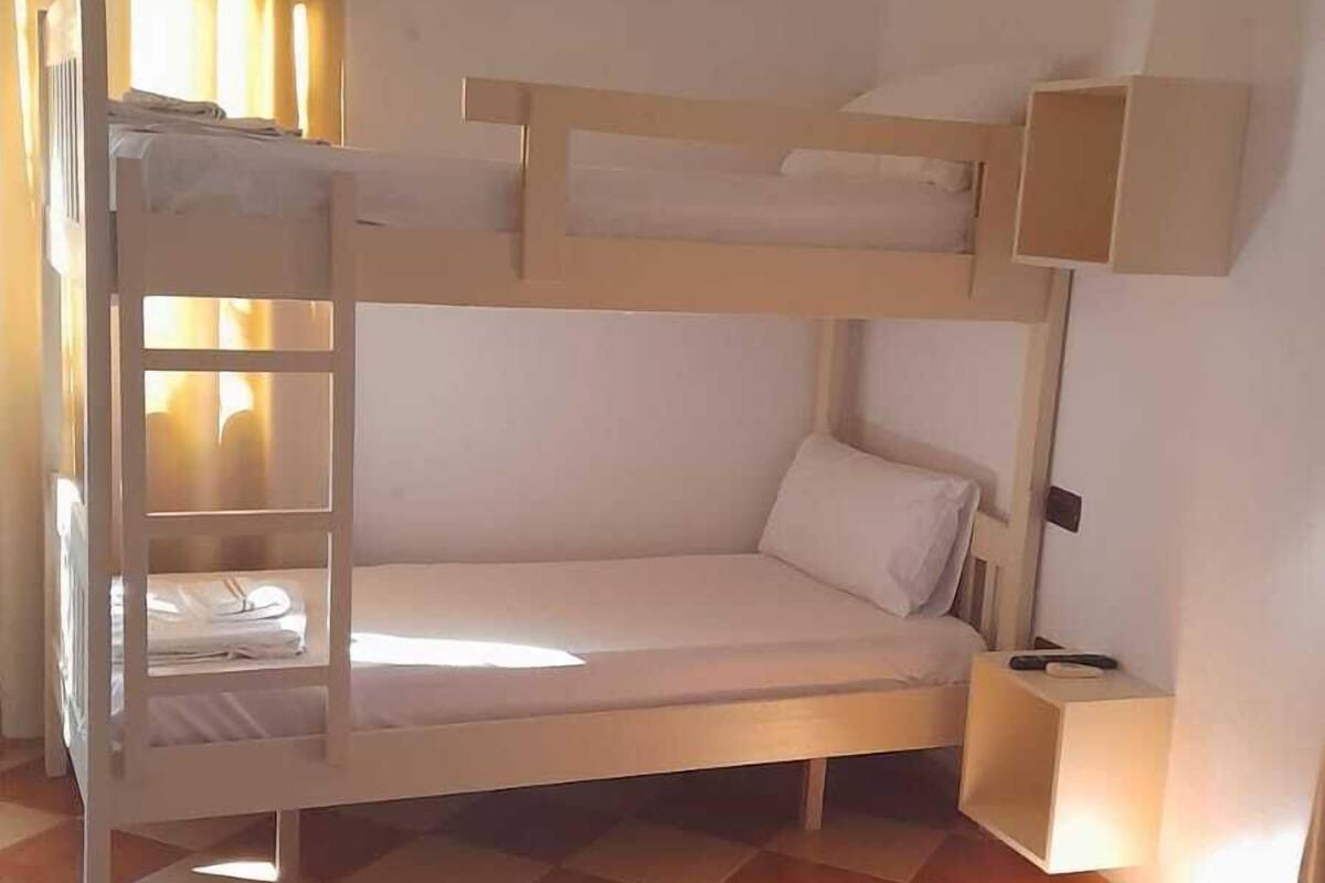 A bunk bed room with a checkered floor, a red blanket, and a white towel on the lower bunk.