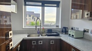 Una cucina con un lavello doppio, una finestra vista edifici e un tostapane sul bancone.