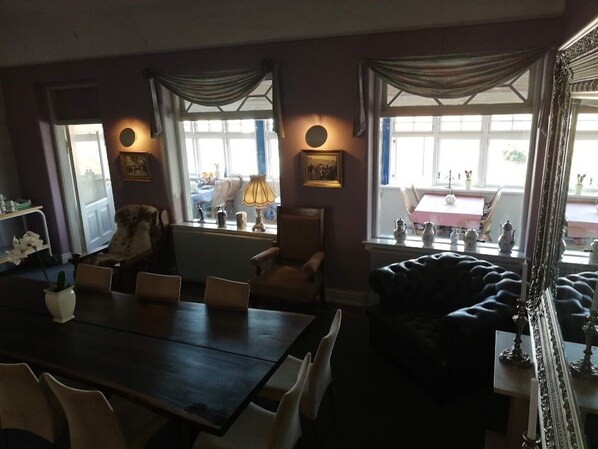 A dining area with a table and chairs, a sofa, and a window with curtains. - Det Gamle Hotel Rudkøbing (Rudkøbing)
