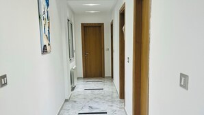 A hallway with white walls, wooden doors, and a marble floor. - Tranquil Mrezga Getaway: Near Beach & Hammamet Fun (Mrezga)