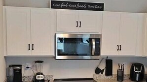 A kitchen with white cabinets, a stainless steel microwave, a stove, and a coffee maker. - New Home w/Patio near Laughlin/Mohave/Colorado Riv (Bullhead City)