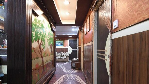 A corridor with wooden paneling, a mural of a tree, and a patterned floor. - Hotel Classic International (Kolkata)