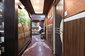 A corridor with wooden paneling, a mural of a tree, and a patterned floor. - Hotel Classic International (Kolkata)