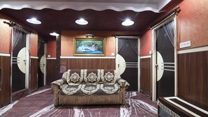 A lobby with a sofa, a framed picture on the wall, and a patterned floor. - Hotel Classic International (Kolkata)