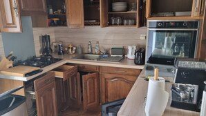 A compact kitchen with wooden cabinets, a gas stove, a coffee maker, and a toaster. - KERYVONNE, FAMILY HOME (Sarzeau)
