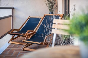 A wooden chair with a blue cushion on a tiled patio.