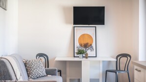 A modern living room with a sofa, two chairs, a white table, a framed artwork, and a flat-screen TV mounted on the wall. - 730A Apartment Lumos (Merano)