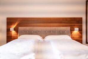A bed with a wooden headboard and two wall-mounted lights.