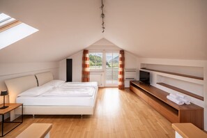 A modern bedroom with a bed, a TV, and a wooden bench. - 733B Apartment Villa Laurin (Caldaro sulla strada del vino)
