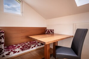 A small room with a wooden bench, a table, and a chair.