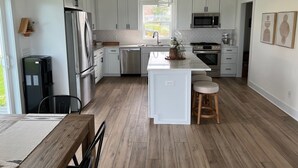 A modern kitchen with white cabinets, stainless steel appliances, and a central island with stools. - Newer build 3-bedroom cottage on peaceful Fremont Lake with AC, WiFi (Fremont)