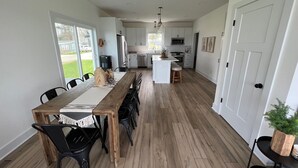 A modern kitchen with white cabinets, a central island, and a dining area with a wooden table and black chairs. - Newer build 3-bedroom cottage on peaceful Fremont Lake with AC, WiFi (Fremont)