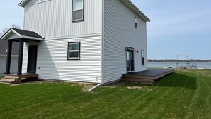A two-story house with a front porch, a deck, and a view of a lake. - Newer build 3-bedroom cottage on peaceful Fremont Lake with AC, WiFi (Fremont)
