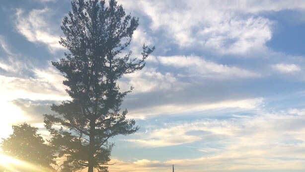 A fire pit with flames, surrounded by a wooden deck, overlooking a body of water with a flag and distant shoreline. - Newer build 3-bedroom cottage on peaceful Fremont Lake with AC, WiFi (Fremont)