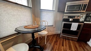 Una cocina compacta con una mesa redonda, una silla, un microondas y un horno.