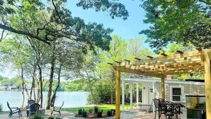 A wooden deck with outdoor furniture, a grill, and a view of a lake.