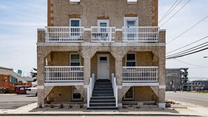 A two-story building with a stone facade, a central entrance with a door, and a staircase leading to the ground floor. - Oceanfront charming 2 bedroom 30 second walk to the beach (Seaside Heights)