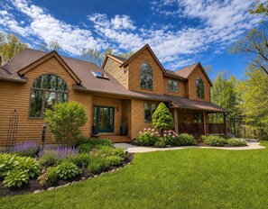 A two-story house with a front porch, large windows, and a well-maintained lawn.