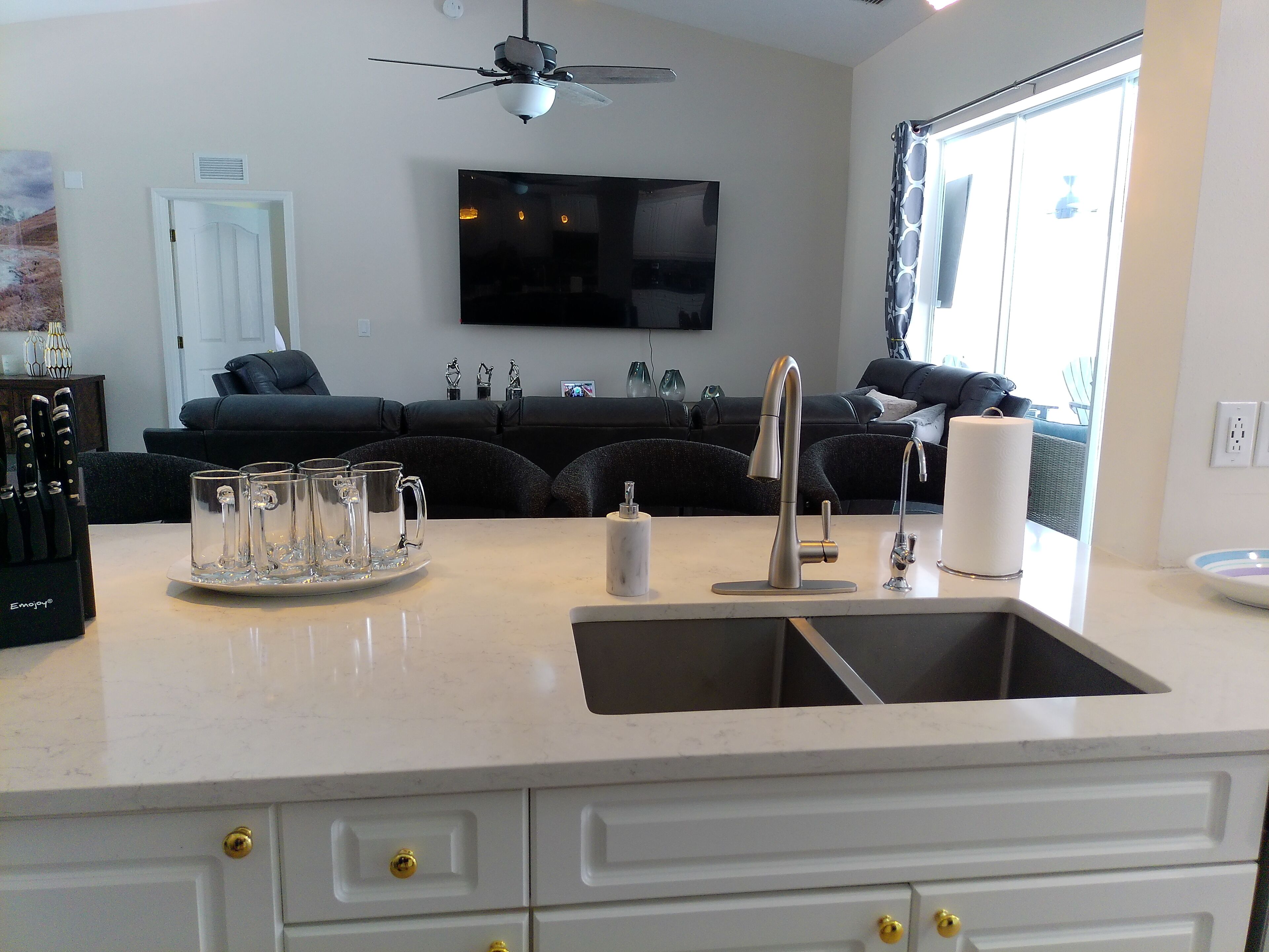 A modern kitchen with a sink, countertop, and a dining area with a sofa and table.