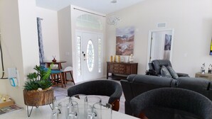 A living room with a sofa, a dining table with chairs, a potted plant, and a glassware set on the table. - Villa Varona, Private Heated Pool Included- No extra fee (Lake Placid)