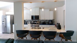 A modern kitchen with white cabinets, stainless steel appliances, and a central island with chairs. - Villa Varona, Private Heated Pool Included- No extra fee (Lake Placid)