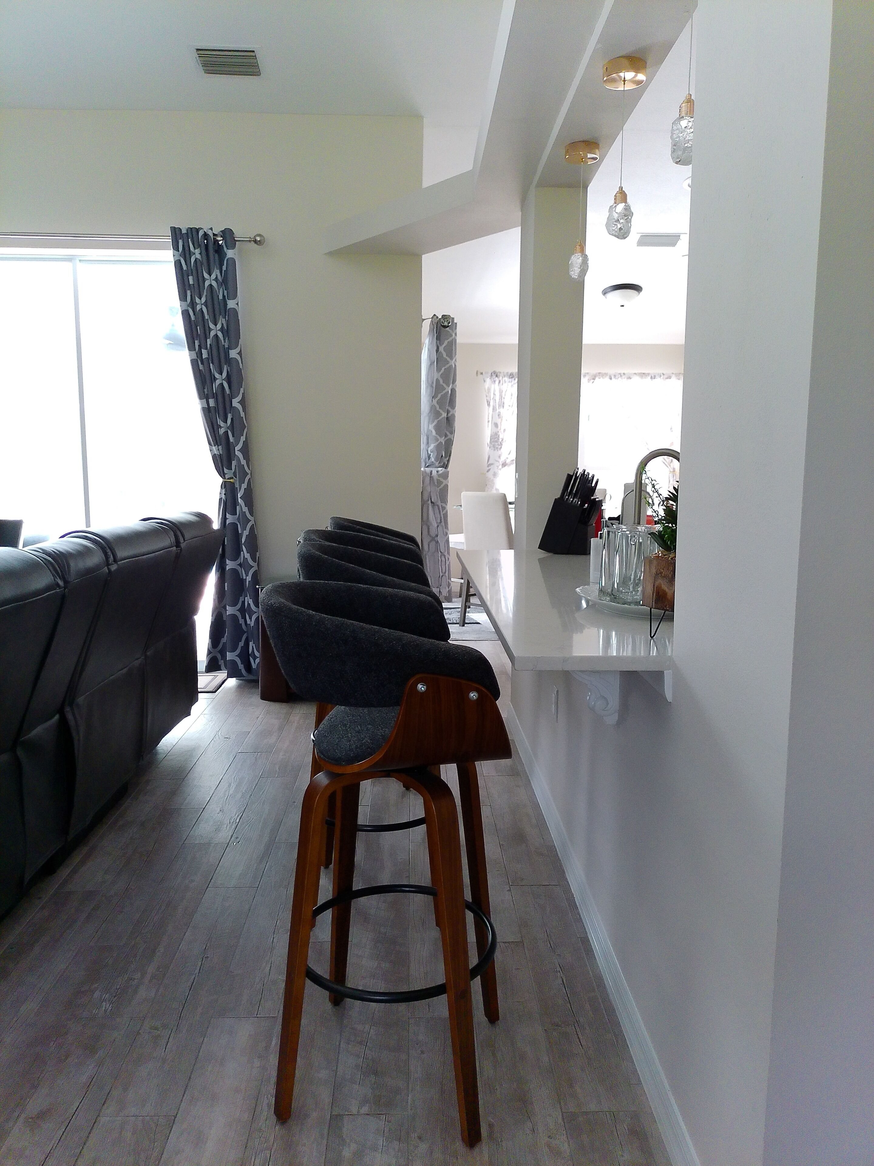 A modern kitchen with a bar area, a dining table, and a sofa.