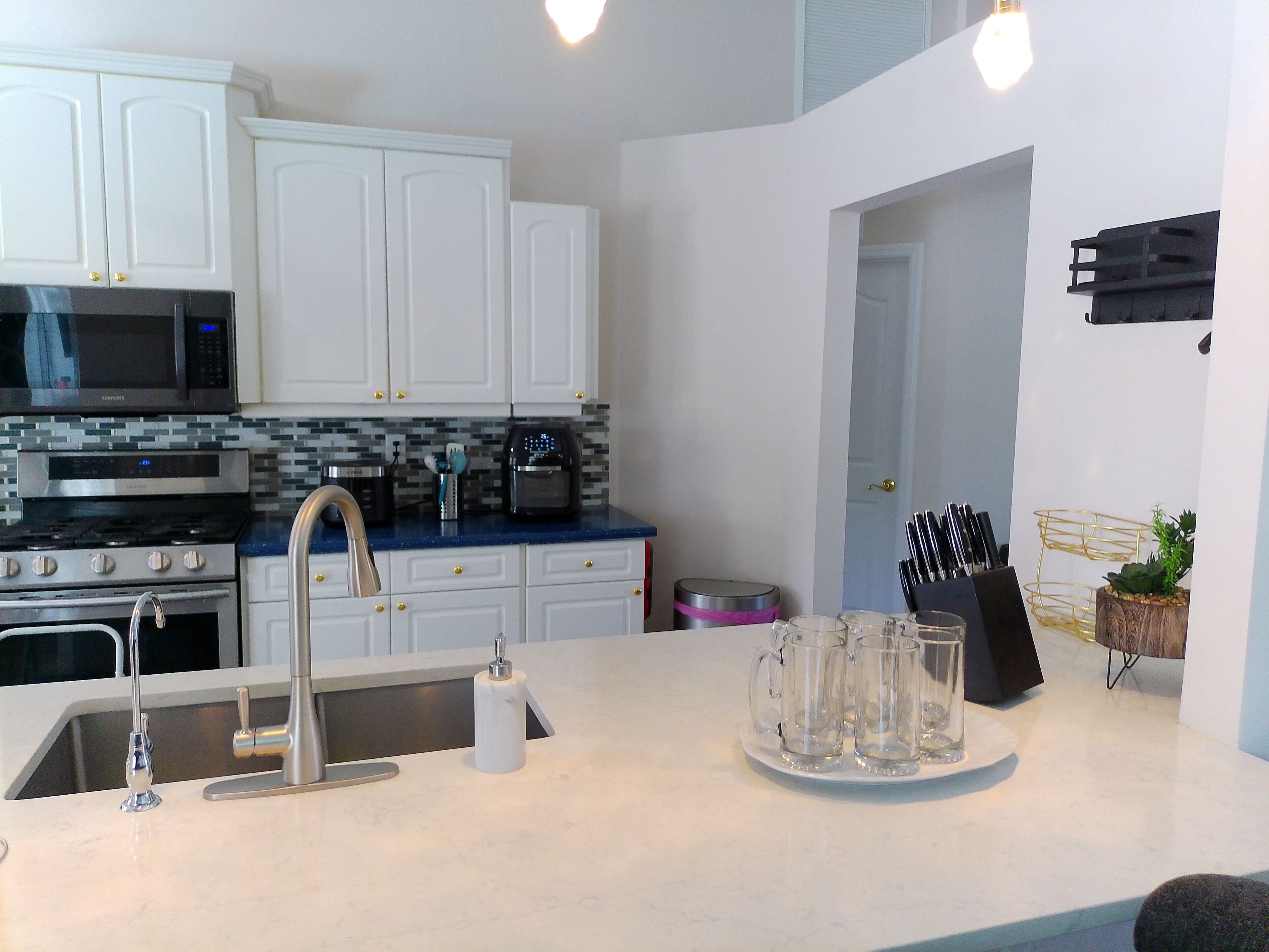 A modern kitchen with white cabinets, stainless steel appliances, and a blue countertop.