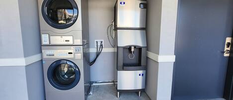 A laundry facility with a front-loading washer and dryer, a water dispenser, and a control panel.