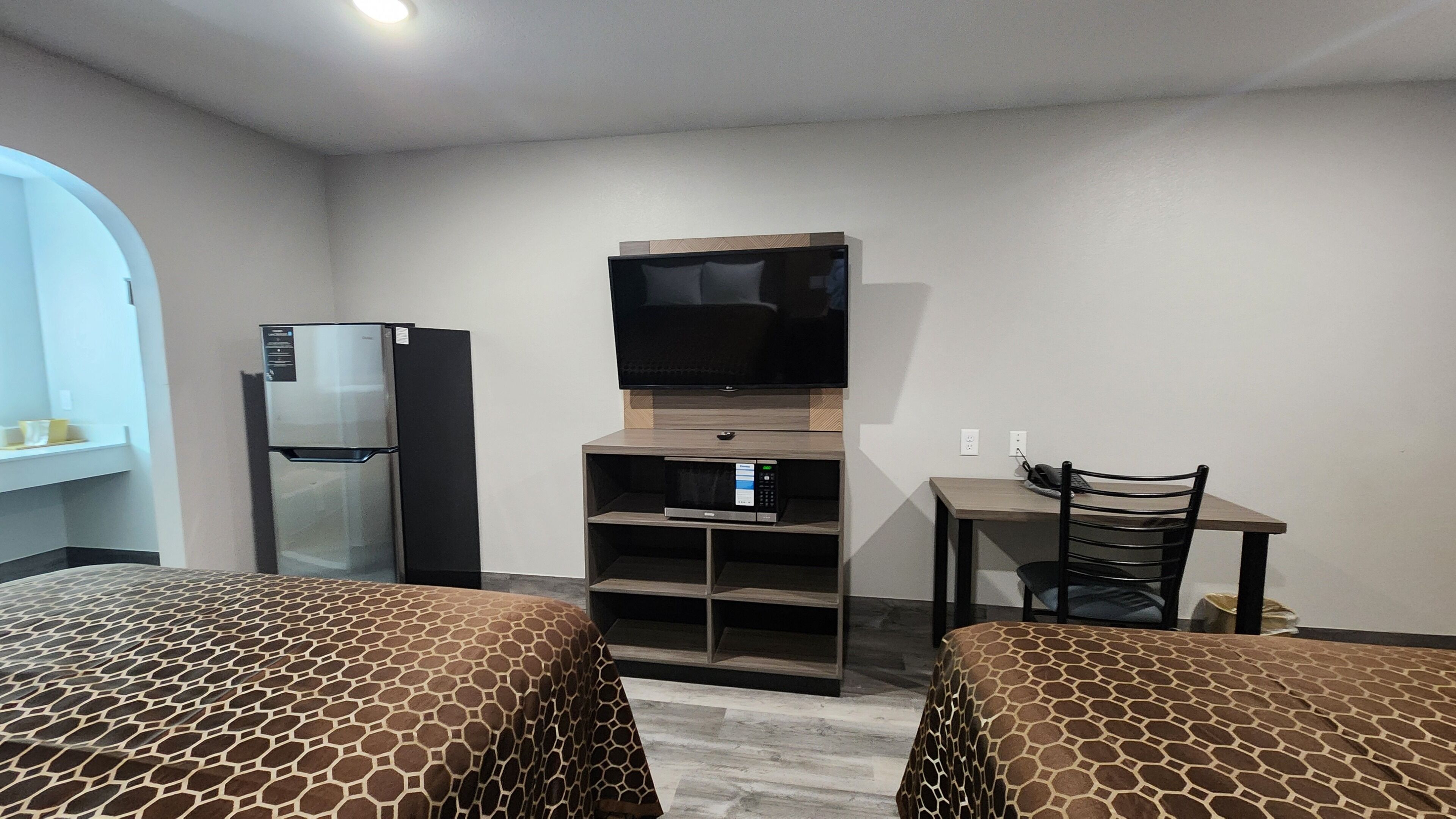 A hotel room with two beds, a television, a refrigerator, and a microwave.