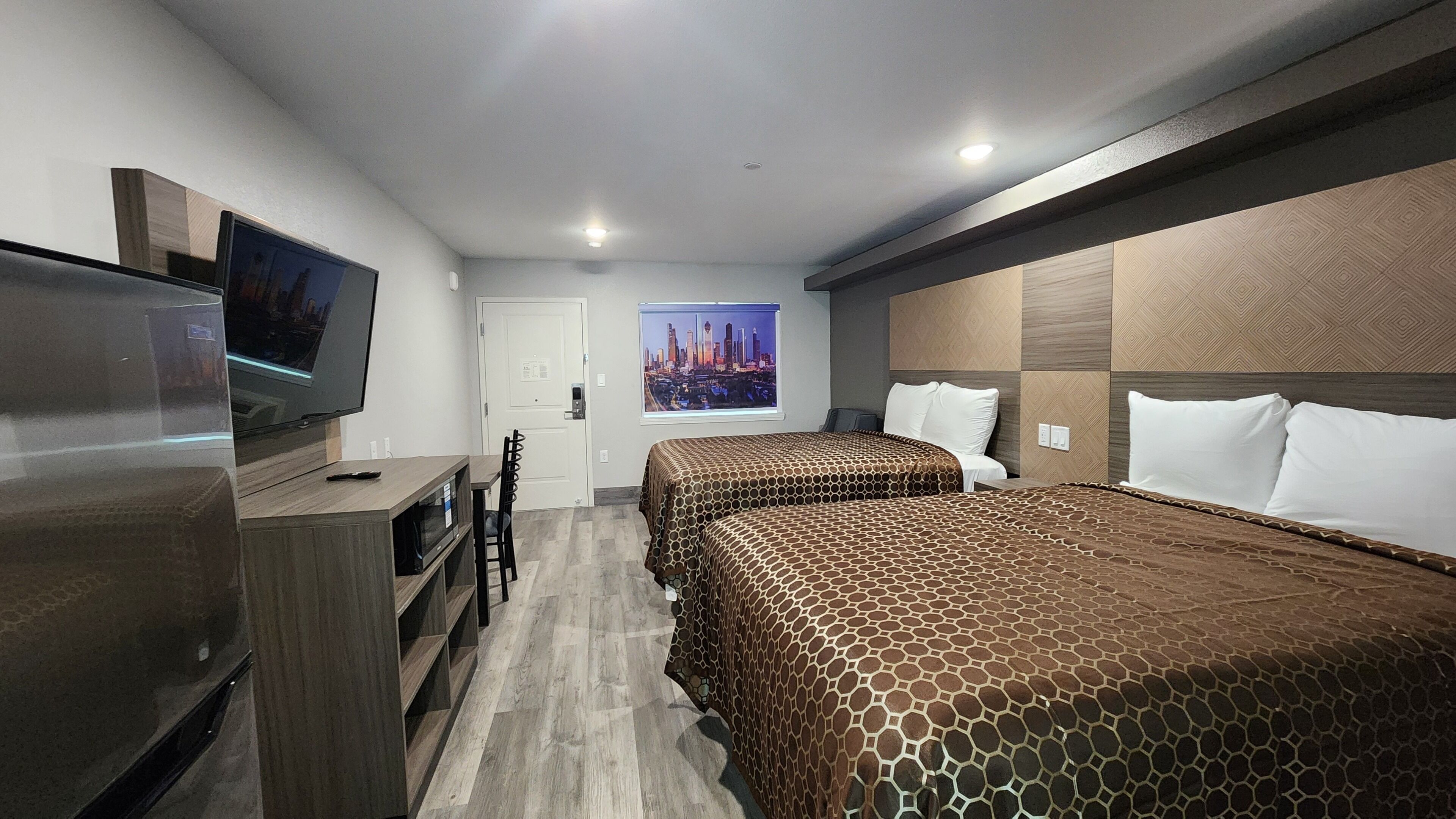 Een hotelkamer met twee bedden, een televisie, een bureau en uitzicht op de stad.