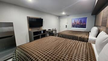 A hotel room with a large bed, a TV, a desk, and a cityscape view.