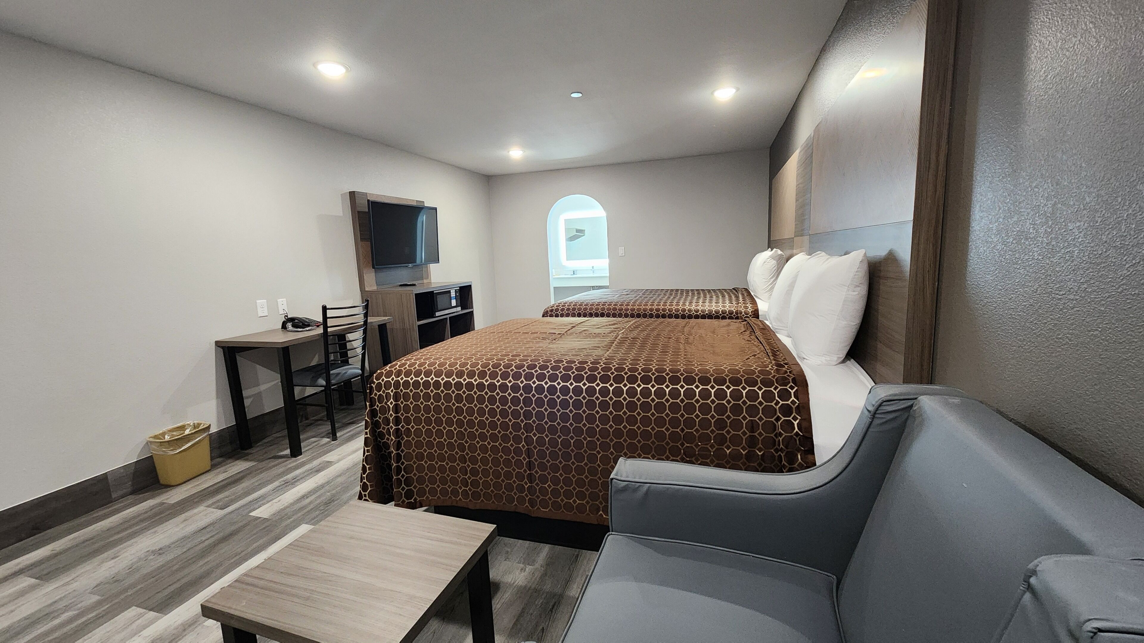 Una habitación de hotel pequeña con cama, sofá, escritorio y televisor.