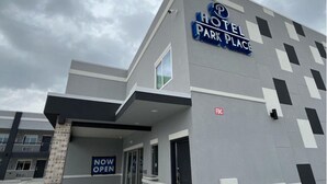 A hotel with a 'NOW OPEN' sign, a parking lot, and a modern architectural design. - Hotel Park Place (Houston)
