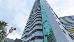 A tall, modern building with multiple balconies and a glass facade. - CJC Short Stay Blue Ocean (Natal)