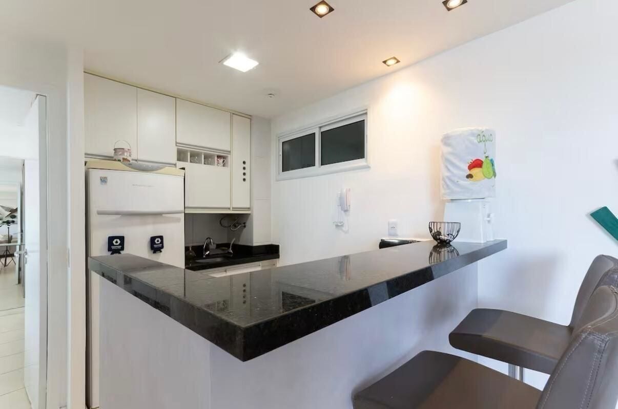 A modern kitchen with white cabinets, a black countertop, and a window above the sink.
