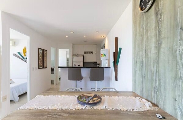 Una cocina moderna con armarios blancos, un refrigerador y un comedor con una mesa para dos.
