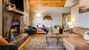 Un accogliente soggiorno con camino in pietra, soffitto in legno e una grande finestra.