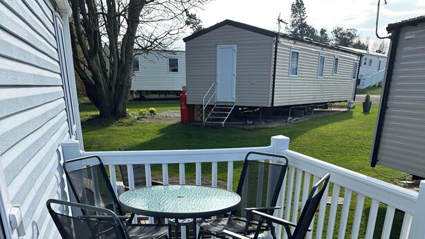 A deck with a table and chairs, surrounded by white railings. - Tranquil Caravan Retreat by the Seaside, Portseton (Prestonpans)