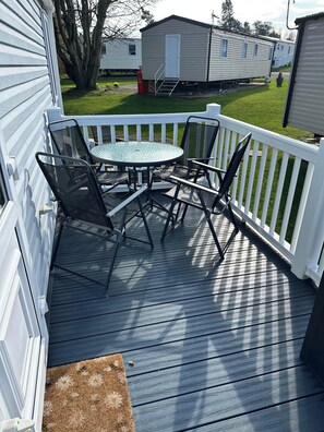 Une terrasse avec une table et des chaises, entourée de rampes blanches.