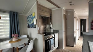 A compact kitchen with a dining area, a painting on the wall, and a view of the adjacent room. - Tranquil Caravan Retreat by the Seaside, Portseton (Prestonpans)