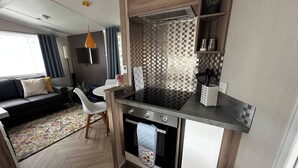A compact kitchenette with a stove, oven, and a small countertop. - Tranquil Caravan Retreat by the Seaside, Portseton (Prestonpans)