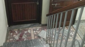 A staircase with a metal railing leading to a wooden door with a handle. - Saraogi Homestays (Varanasi)