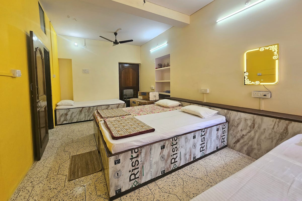 A hotel room with two beds, a ceiling fan, a mirror, and a shelf with toiletries.