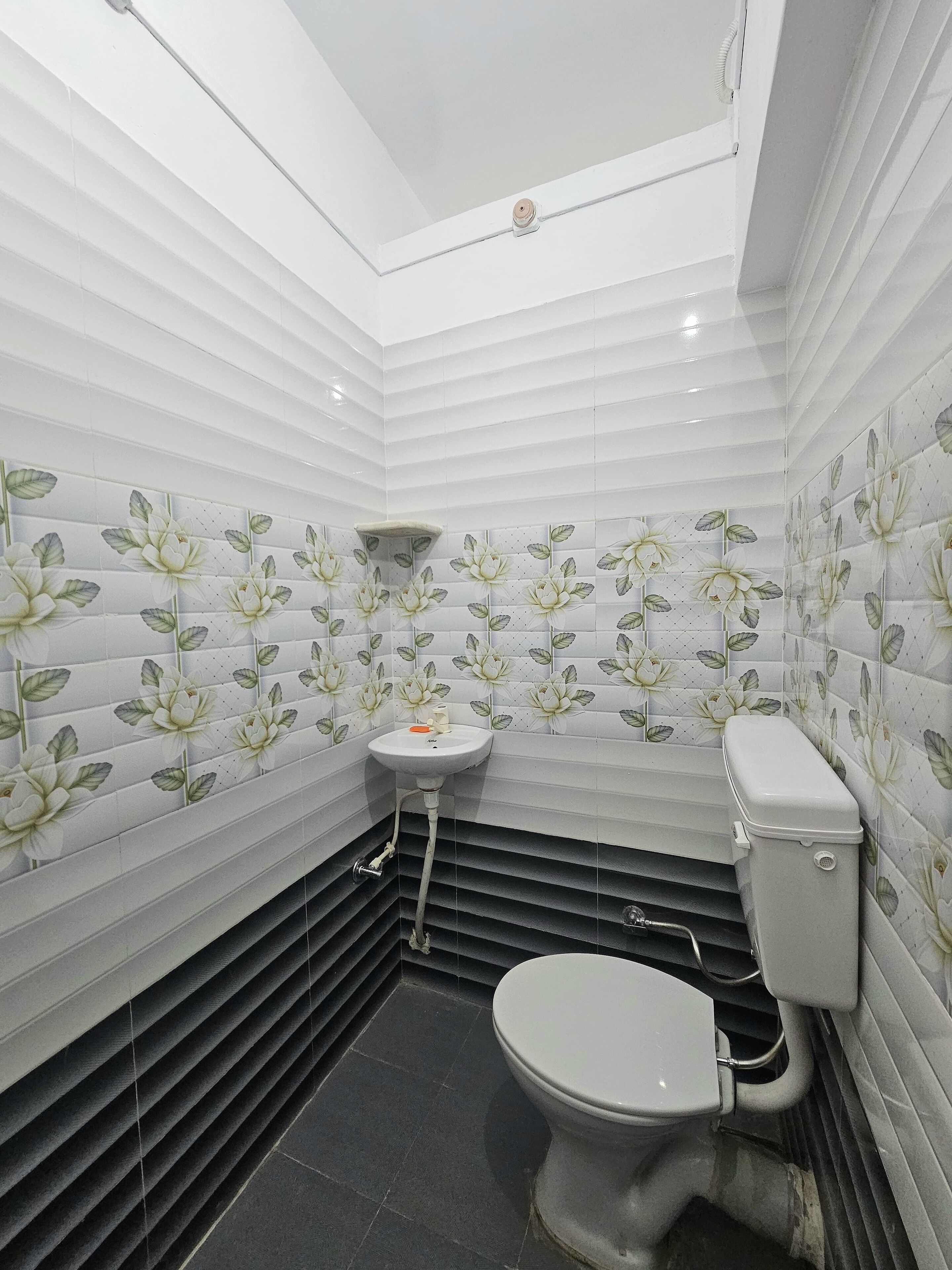 A bathroom with white tiled walls, a black floor, and a toilet.
