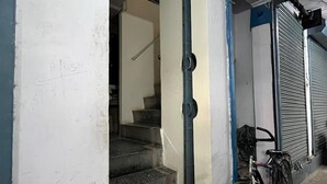 A building entrance with a staircase leading inside, a bicycle parked outside, and a closed shutter door. - Saraogi Homestays (Varanasi)
