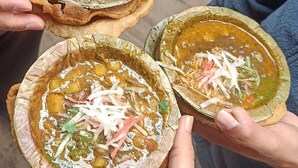 Three bowls of soup with various toppings, held by individuals. - Saraogi Homestays (Varanasi)