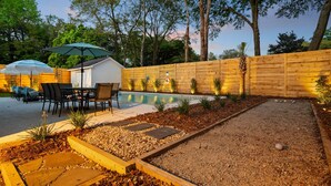 A backyard with a pool, patio furniture, and a wooden fence.