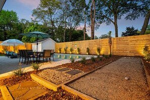 Un jardin avec une piscine, du mobilier de jardin et une clôture en bois.