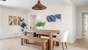 Un comedor con mesa de madera y banco, una lámpara colgante y decoración en la pared.
